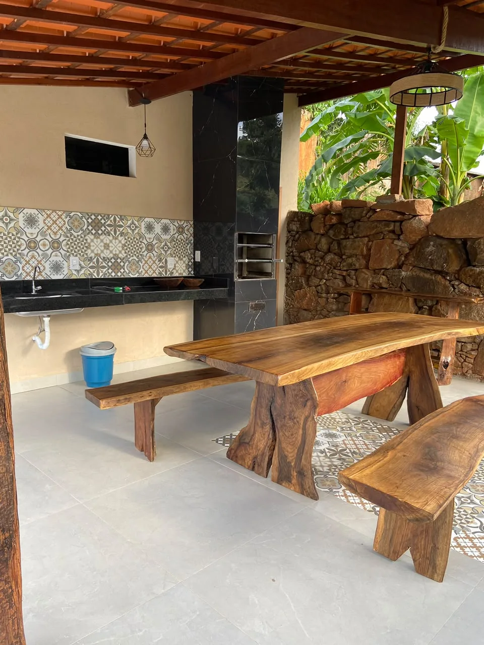 Área gourmet com mesa de madeira e churrasqueira